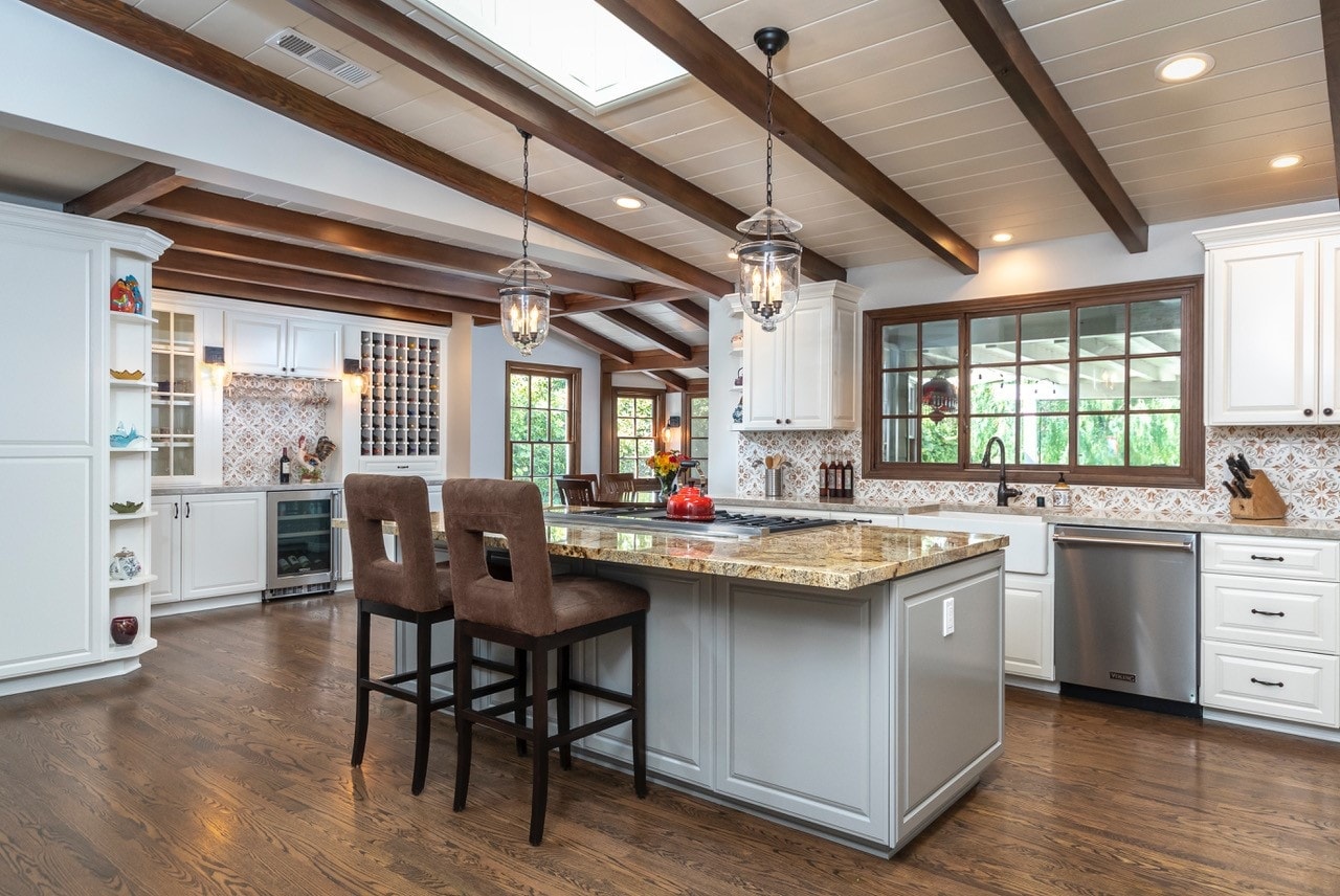 Full kitchen view with skylights, wood beams, granite island and bar seating — La Cañada