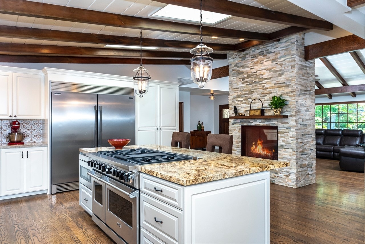 Wide-angle kitchen with wood beam ceiling, granite island and wine storage — La Cañada